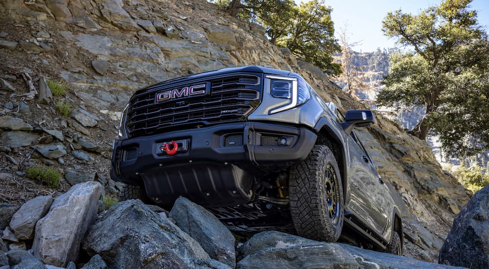 A grey 2025 GMC Sierra 1500 AT4x AEV driving over rocks.