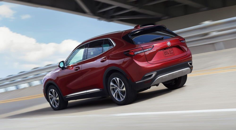 Rear of a red 2023 Buick Envision driving under a bridge.