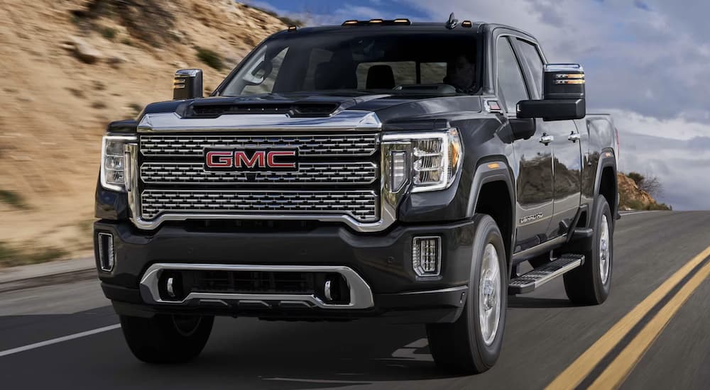 A black 2023 GMC Sierra 2500 HD Denali driving down a road
