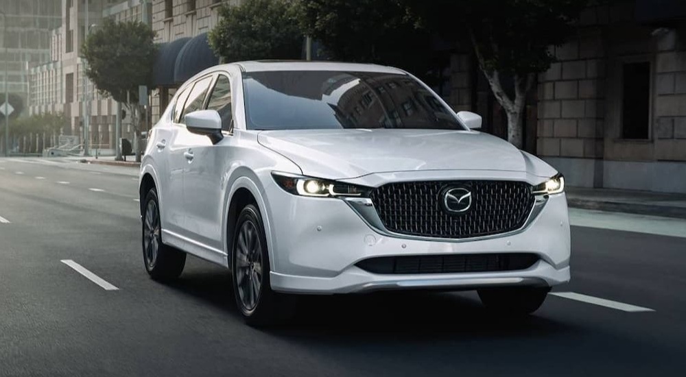 White 2021 Mazda CX-5 driving through a city.