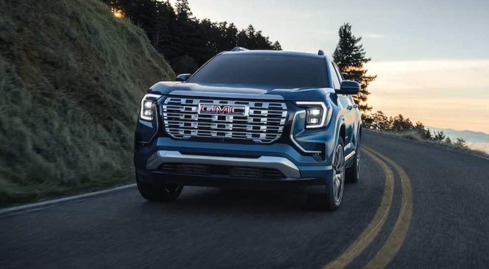 A blue 2026 GMC Terrain Denali driving on a highway.