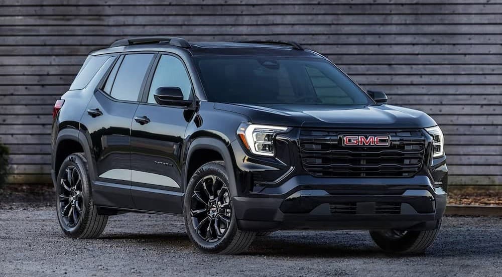 A black 2026 GMC Terrain parked near a wooden building.