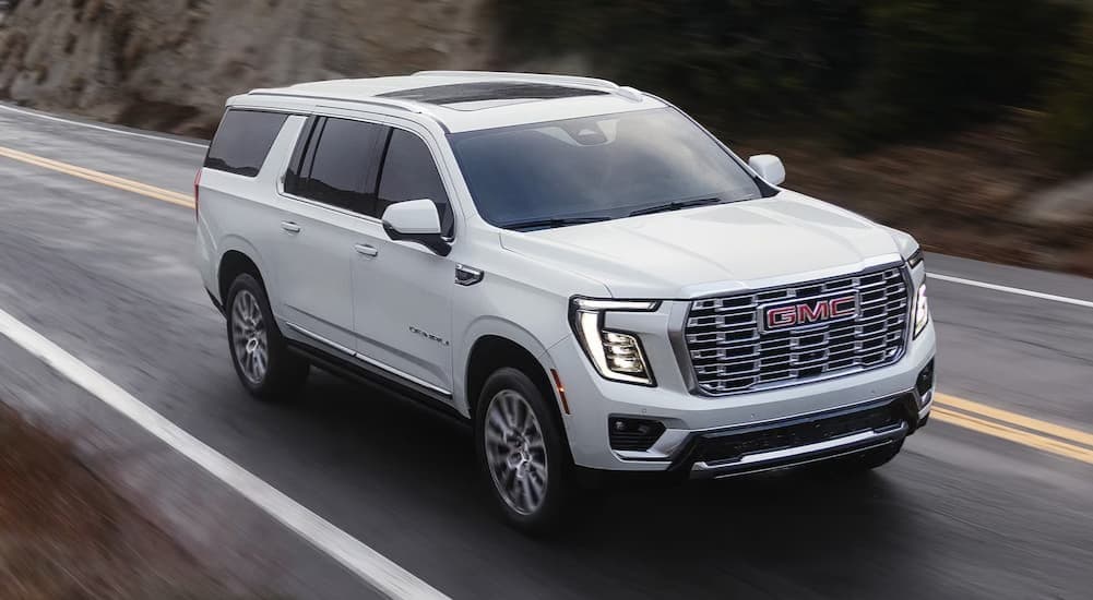 A white 2026 GMC Yukon driving on a highway.