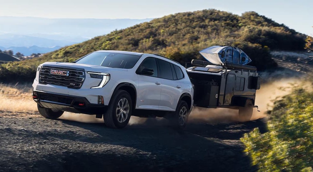 A white 2026 GMC Acadia AT4 towing a trailer.