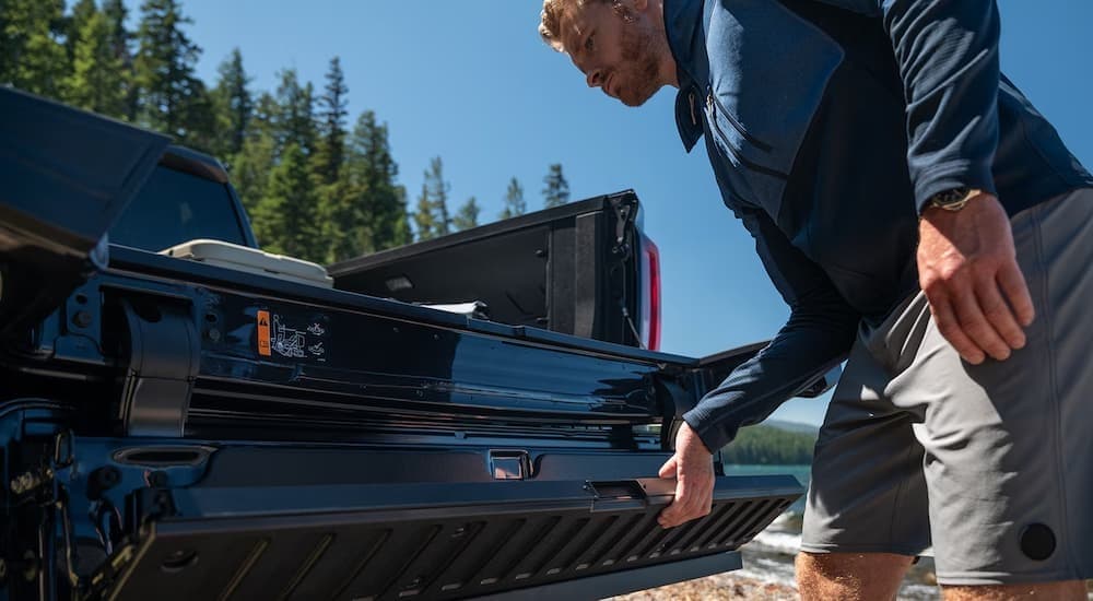 A person opening the tailgate on a black 2026 GMC Sierra 1500.