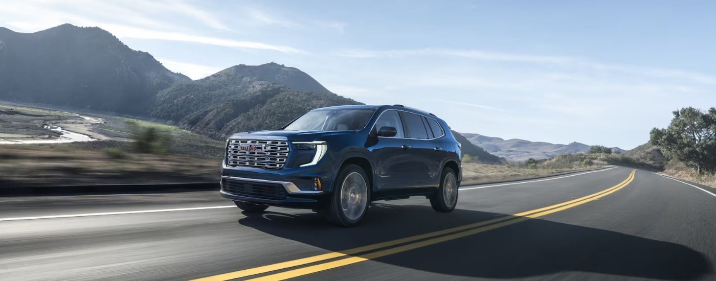 Black 2026 GMC Acadia Denali driving on an open road