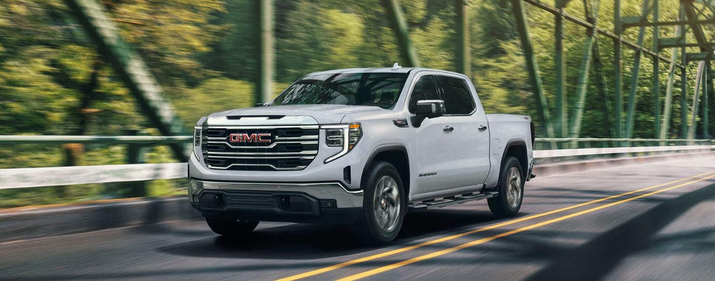 White 2026 GMC Sierra 1500 driving over a bridge.