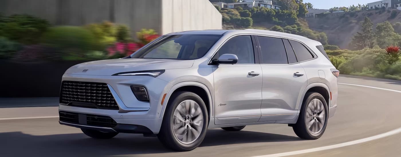 White 2027 Buick Enclave driving around a bend.