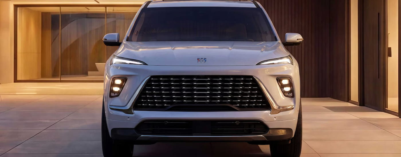 Front of a white 2027 Buick Enclave parked in front a building.