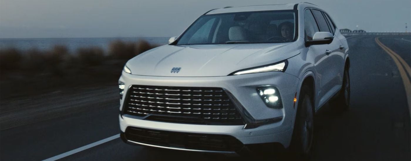 A white 2026 Buick Enclave driving by the ocean.