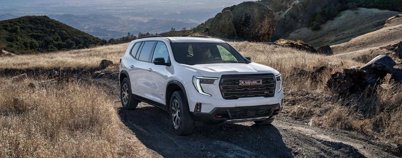A white 2027 GMC Acadia AT4 driving off road.