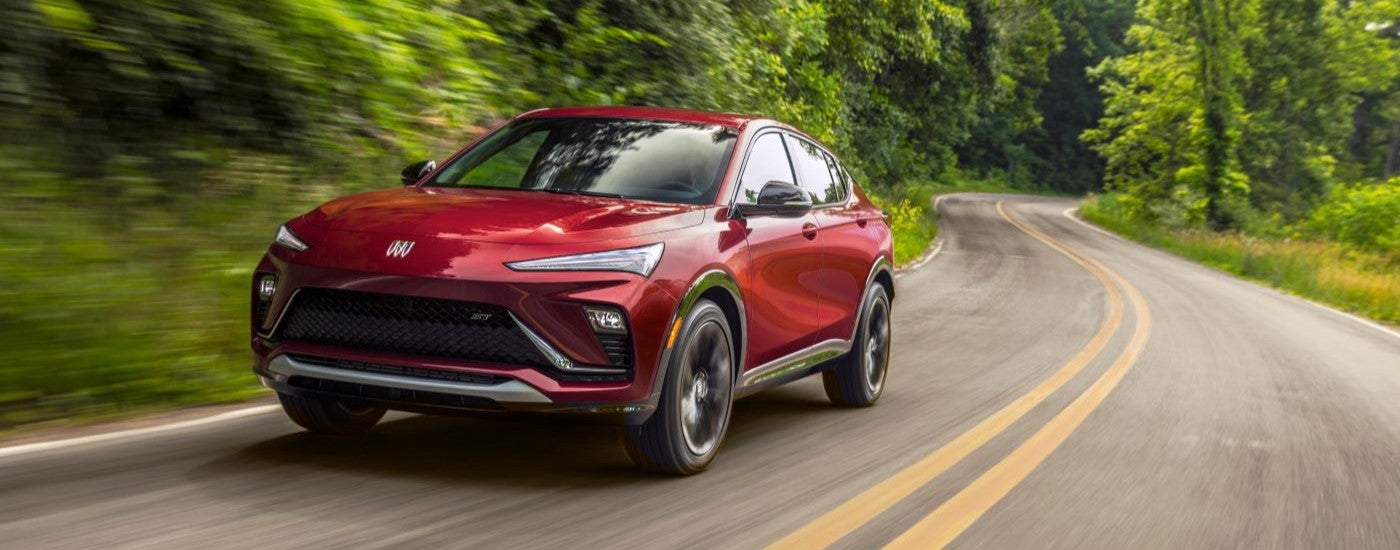 Red 2024 Buick Envista ST driving down a winding road from a Buick dealer near Hopkins.