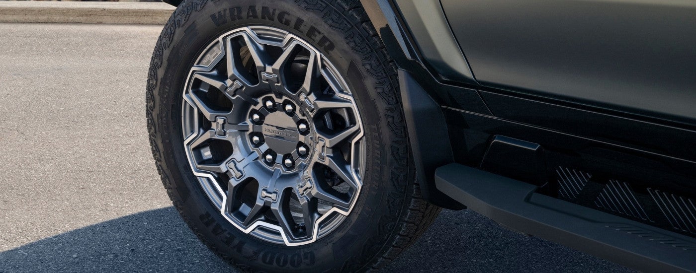 A close up shows a chrome wheel on a green 2024 GMC Hummer EV.
